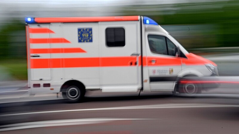 Ein Krankenwagen fährt mit Blaulicht auf einer Straße.