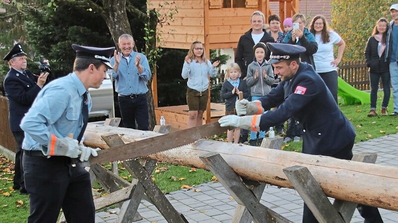 Kommandant Florian Obermeier und Vorsitzender Bernhard Dachs beim Zersägen des Baumstammes.