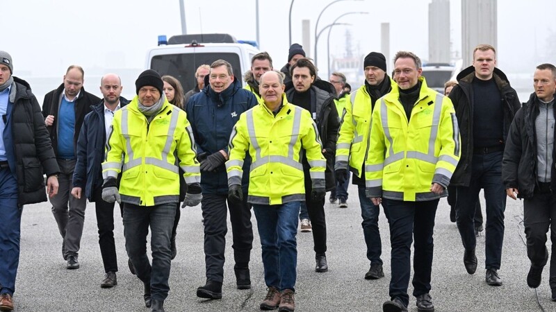 Robert Habeck, Olaf Scholz und Christian Lindner bei der Ankunft auf einem Pier.