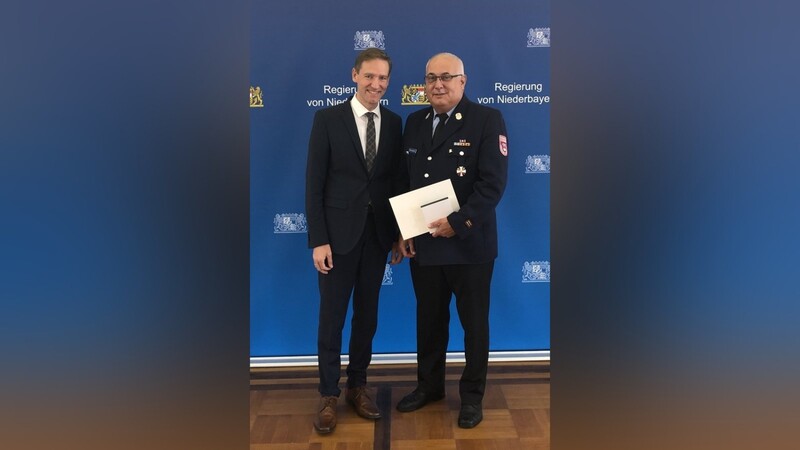 Regierungspräsident Rainer Haselbeck überreicht Franz Saxstetter, Kreisbrandmeister im Landkreis Landshut, das Steckkreuz des Feuerwehr-Ehrenzeichens.