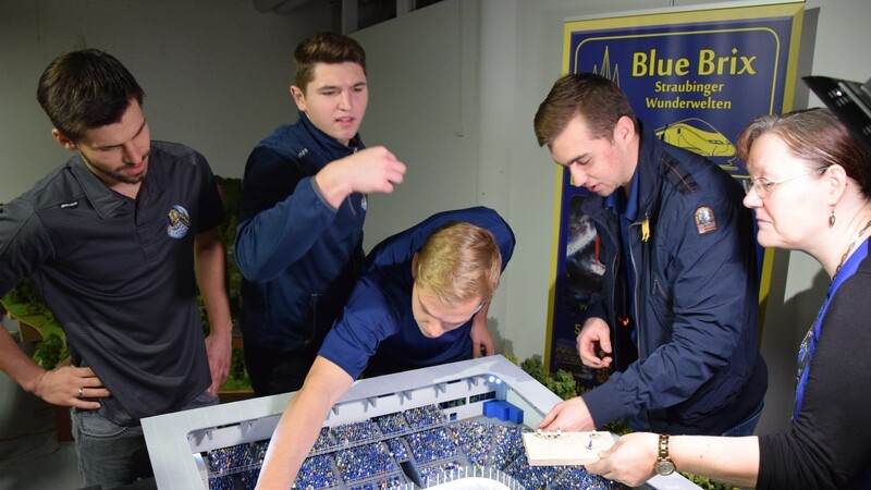 Benedikt Kohl (v.l.) schaut prüfend zu, Vladislav Filin schaut bei einem Miniatur-Spieler genau hin, Tim Brunnhuber platziert den gegnerischen Torwart und Sven Ziegler darf mit der Pinzette den Puck aufs Eis legen. Bluebrix-Chefin Elisabeth Linert reicht den Spielern die Spieler. Vielleicht kommt das Stadion auch noch ins Stadion.