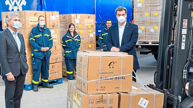 Der Vorstandsvorsitzende der Siemens AG Joe Kaeser (links) und Ministerpräsident Dr. Markus Söder bei der Übergabe der Spende der Siemens AG von medizinischen Masken in Garching. Im Hintergrund drei Mitglieder des Technischen Hilfswerkes Roding.