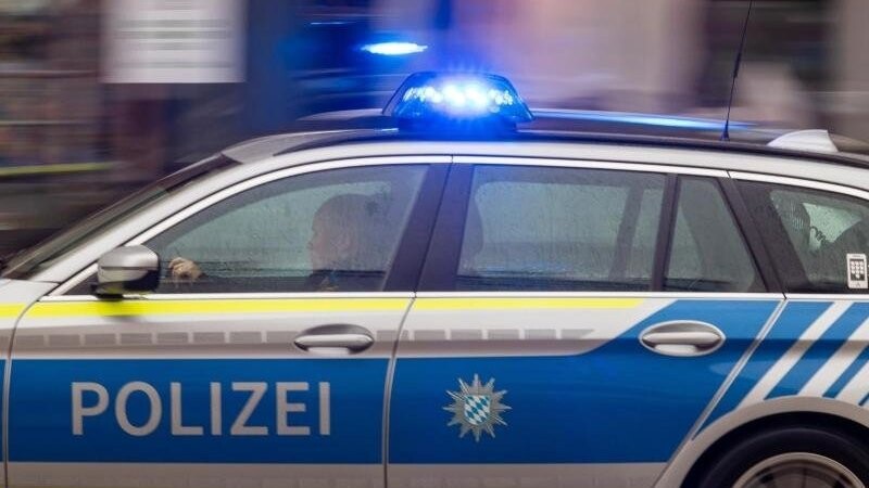 Ein Fahrzeug der bayerischen Polizei fährt mit Blaulicht durch die Innenstadt.