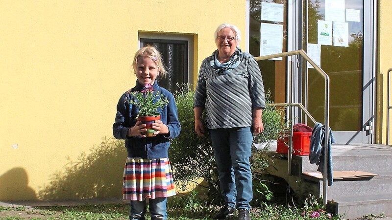 Für ein Stück mehr Normalität in der Coronakrise: Erstklässlerin Constanze und Gartenbauvereinsvorsitzende Berta Trautmann beim Abholen des kreativ gestalteten Muttertagsgeschenks vor der Grundschule St. Martin.