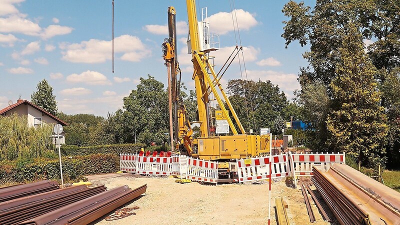 Seit Montag werden mithilfe schweren Geräts am Standort der kürzlich abgebrochenen und bald neu entstehenden Brücke über den Gansmühlbach Stützspundwände in das Erdreich getrieben, um die weiteren Bauarbeiten dieses Bauabschnitts zu ermöglichen.