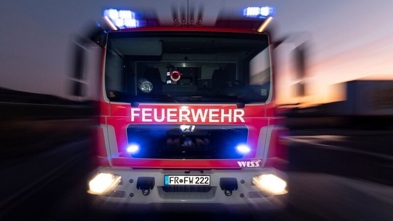 Ein Feuerwehrfahrzeug steht mit eingeschaltetem Blaulicht auf einer Straße.