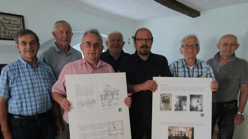 Heimatforscher Hans Seidl, Chronist Ernst Gruß, Archäologe Bernhard Zirngibl und zweiter Vorsitzender Anton Paukner präsentieren im Beisein weiterer Vorstandschaftsmitglieder zwei Schautafeln über das gut erforschte Museumsgebäude.