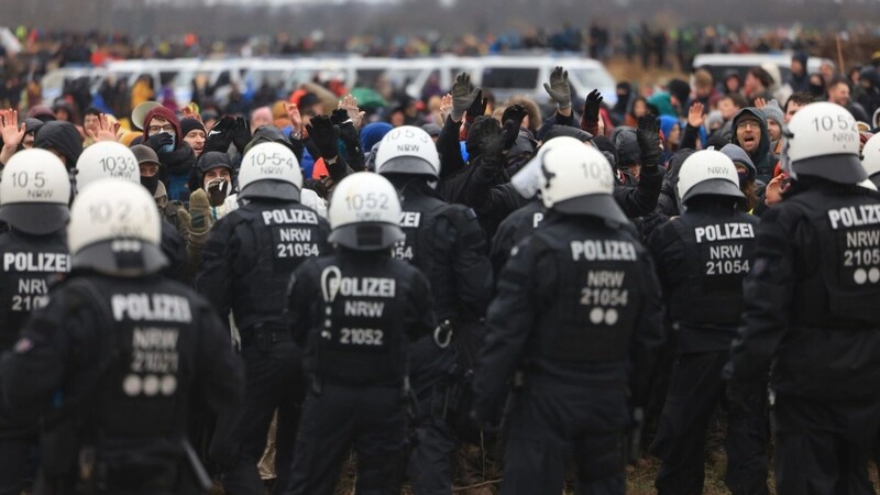 Polizisten und Demonstranten stehen sich bei der Demonstration von Klimaaktivisten am Rande des Braunkohletagebaus bei Lützerath gegenüber.