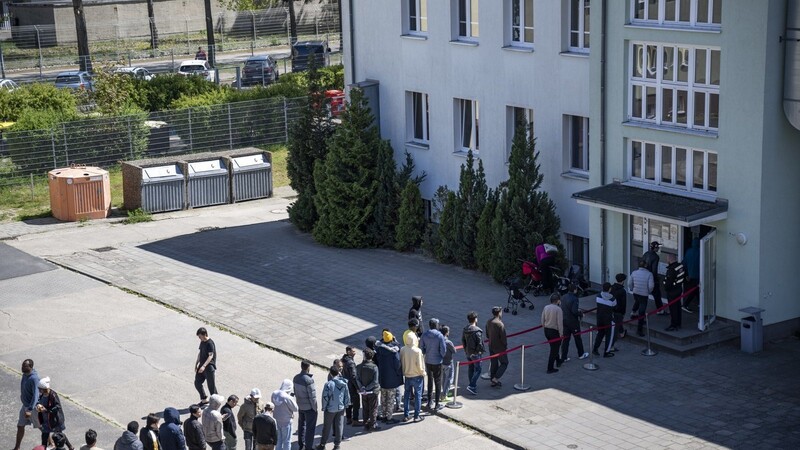 Migranten stehen in einer Schlange in der Erstaufnahme-Einrichtungen (EAE) des Landes Brandenburg in Eisenhüttenstadt. Die SPD ringt um ihren Migrationskurs, wobei Bundeskanzler Olaf Schol von der dänischen Regierungschefin und Sozialdemokratin lernen könnte.