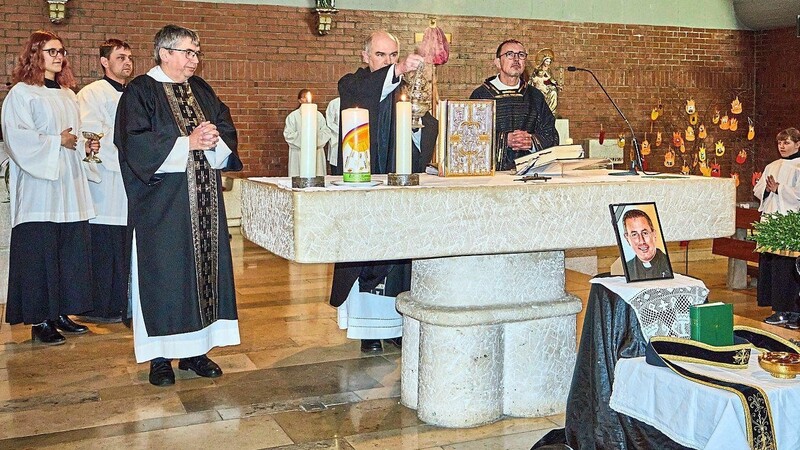 Pfarrer Franz Merl und die beiden Diakone Alfred Dobler und Martin Peintinger am Altar der Dalkinger Kirche. Davor das Bild des verstorbenen Seelsorgers und die priesterlichen Utensilien.