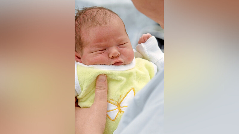 Eine Hebamme hält ein Baby im Arm. Mit verschiedenen Maßnahmen will das bayerische Gesundheitsministerium erreichen, dass wieder mehr Frauen diesen Beruf ausüben, denn in Bayern gibt es zu wenig Hebammen.