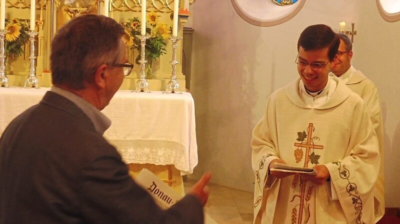 PGR-Vorsitzender Rolf Schwinger überreicht Neupriester Magnus Pöschl ein Exemplar des Donau-Anzeigers.