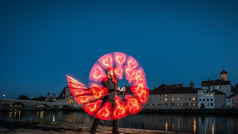 Auch Lichteffekte gehören mittlerweile zu den Shows des 41-Jährigen: Thomas Dietz jongliert vor der Altstadtkulisse Regensburgs.