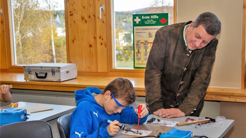 An der Schöllnacher Mittelschule kann der Nachwuchs MINT-Berufe testen. Landrat Christian Bernreiter - er beobachtet hier einen Schüler beim Löten eines Lautsprechers - findet das Gemeinschaftsprojekt toll.