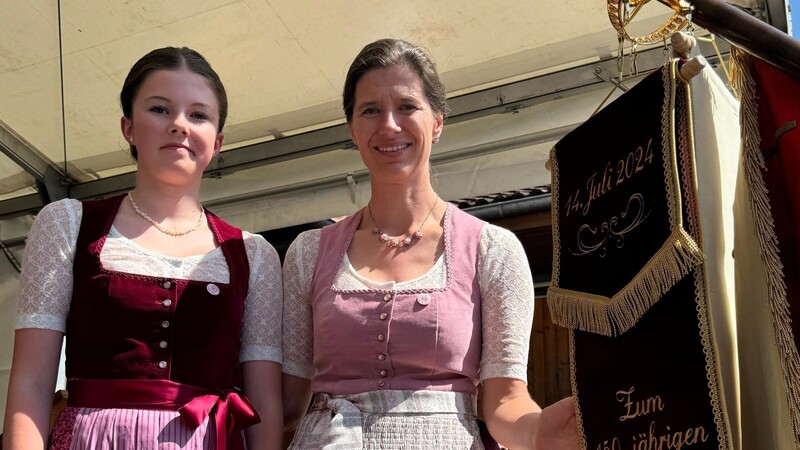 Festdame Theresa Rohrmaier und Fahnenmutter Andrea Rohrmaier heften die Bänder an die Fahne.