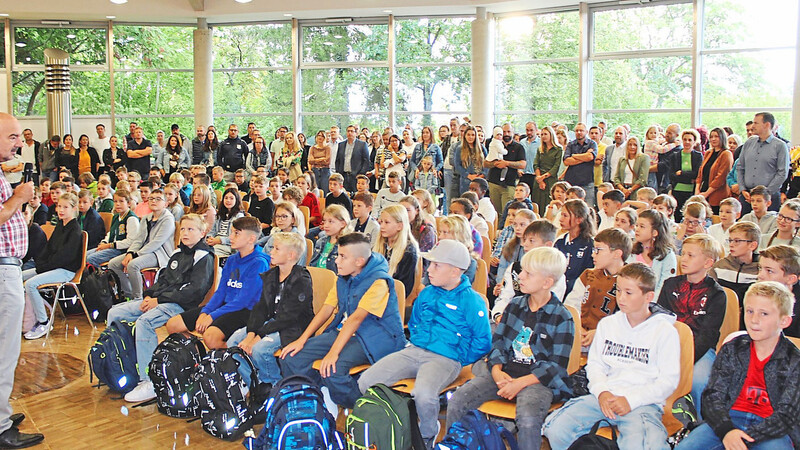 Eltern und Schüler haben sich in der Aula versammelt, wo sie zum Neubeginn am Gymnasium von Schulleiter Claus Gigl begrüßt werden.