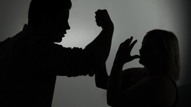 Ein als Silhouette abgebildeter Mann droht einer Frau mit der Faust. Foto: Jan-Philipp Strobel/dpa/Illustration/Archivbild