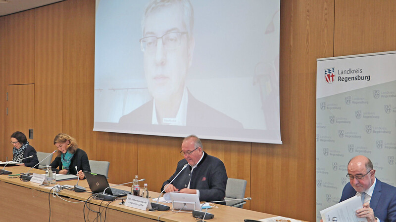 Big brother is watching you: Verbandsgeschäftsführer Robert Kellner berichtete aufgrund einer Quarantänemaßnahme von zu Hause aus via Livestream. Auf dem Podium (von links): Stellvertretende Vorsitzende OB Gertrud Maltz-Schwarzfischer, Landrätin Tanja Schweiger, Vizestellvertreter Landrat Franz Löffler und der Neumarkter Landrat Willibald Gailler.