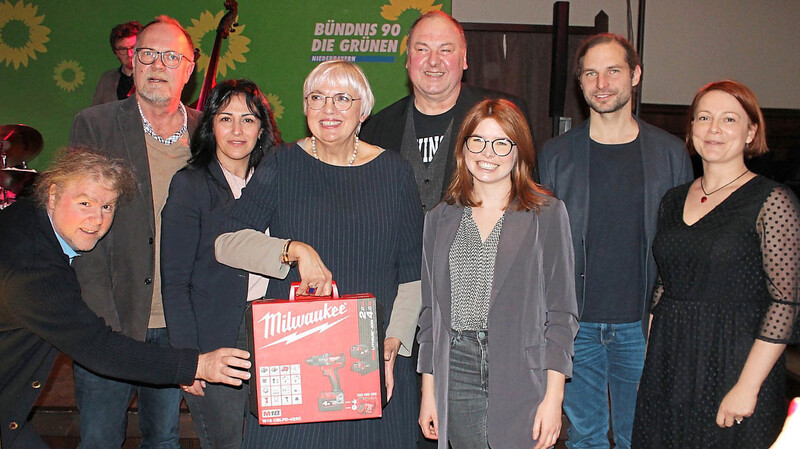 Grünen-Bezirksrat Markus Scheuermann (v.l.), Bezirkstags-Kandidat Kay Hoppe, Landtagskandidatin Feride Niedermeier, Ministerin Claudia Roth mit Bohrmaschine zum Bohren dicker Bretter, MdB Erhard Grundl, MdB Marlene Schönberger, MdL Toni Schuberl und Bezirksrätin Mia Goller. Im Hintergrund Michael "Eumel" Aumer mit Band.