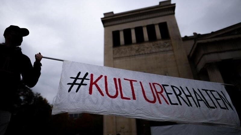 Schon seit Längerem sind Kunst- und Kulturschaffende mit den in ihren Augen unfairen Corona-Maßnahmen unzufrieden - wie diese beiden Männer mit ihrem Banner auf dem Königsplatz in München. (Archivbild)