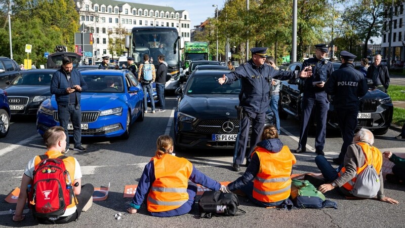 Klimaaktivisten kleben sich im November am Karlsplatz in der Münchner Innenstadt auf die Fahrbahn und blockieren die Straße.