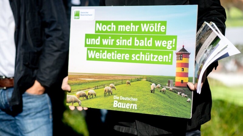 Weidetierhalter demonstrieren mit einem Schild mit der Aufschrift "Noch mehr Wölfe und wir sind bald weg! Weidetiere schützen!" vor Beginn der Umweltministerkonferenz vor dem Tagungshotel.