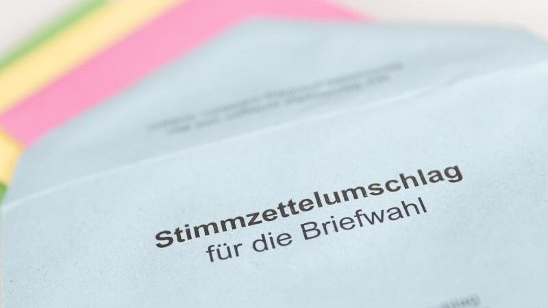 Verschiedene Stimmzettel stecken in einem Stimmzettelumschlag für die Briefwahl.