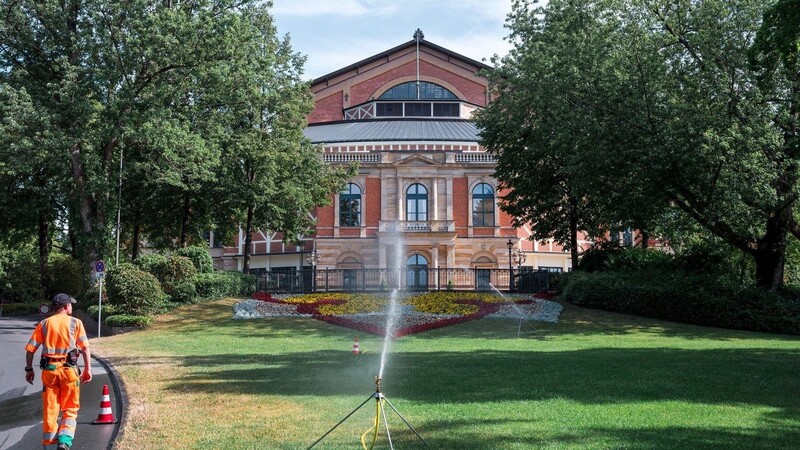 Ein städtischer Mitarbeiter bewässert die Grünfläche vor dem Festspielhaus.