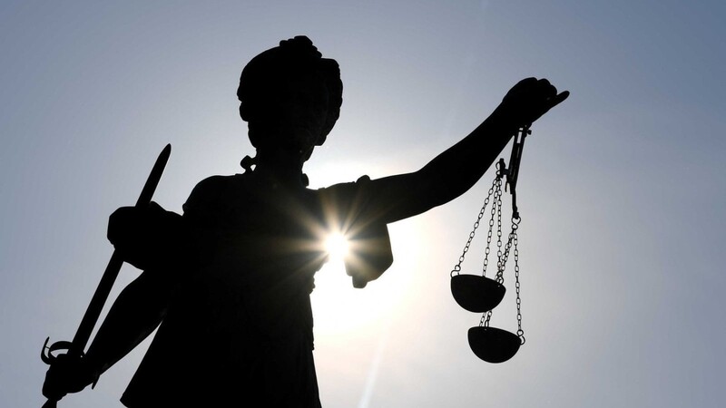 Eine Statue der Justitia steht mit Waage und Schwert in der Hand.