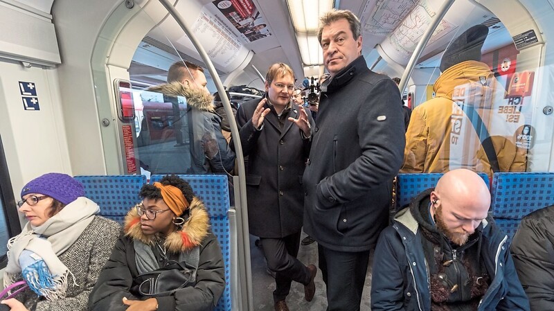 Ministerpräsident Markus Söder (M.) fährt mit der Münchner S-Bahn.