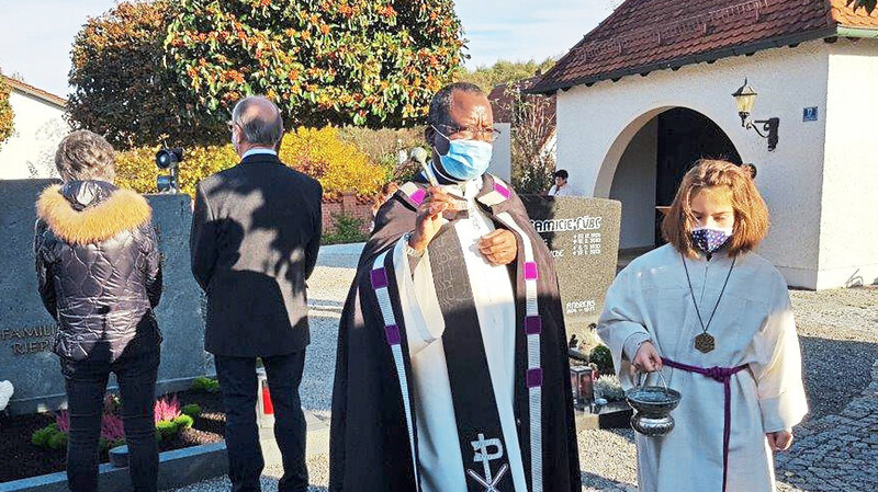 Das Bild zeigt Pfarrvikar Raphael und Ministrantin Helene bei der Gräbersegnung in Oberhaselbach.