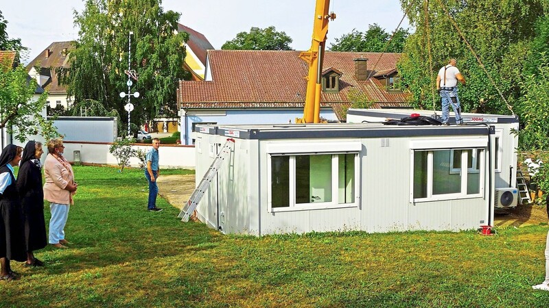 In Schierling wird im Klostergarten, direkt neben dem Kindergarten St. Michael, übergangsweise eine neue Kindergartengruppe in einer Containeranlage eingerichtet, die in diesen Tagen unter Beobachtung (v.l.) der Schwestern Maria und Rosina, zweiten Bürgermeisterin Maria Feigl sowie Hermann Diermeier und Nina Kellner vom gemeindlichen Bauamt geliefert wurde.